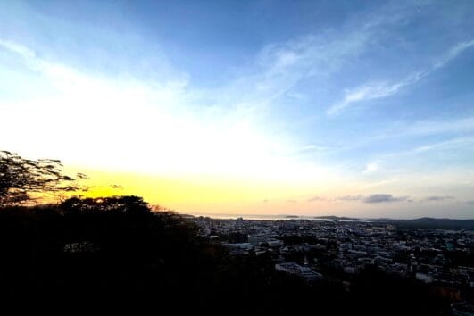 A stunning view from Radar Hill Viewpoint overlooking Patong Beach, Phuket, with golden sky hues and the city below.