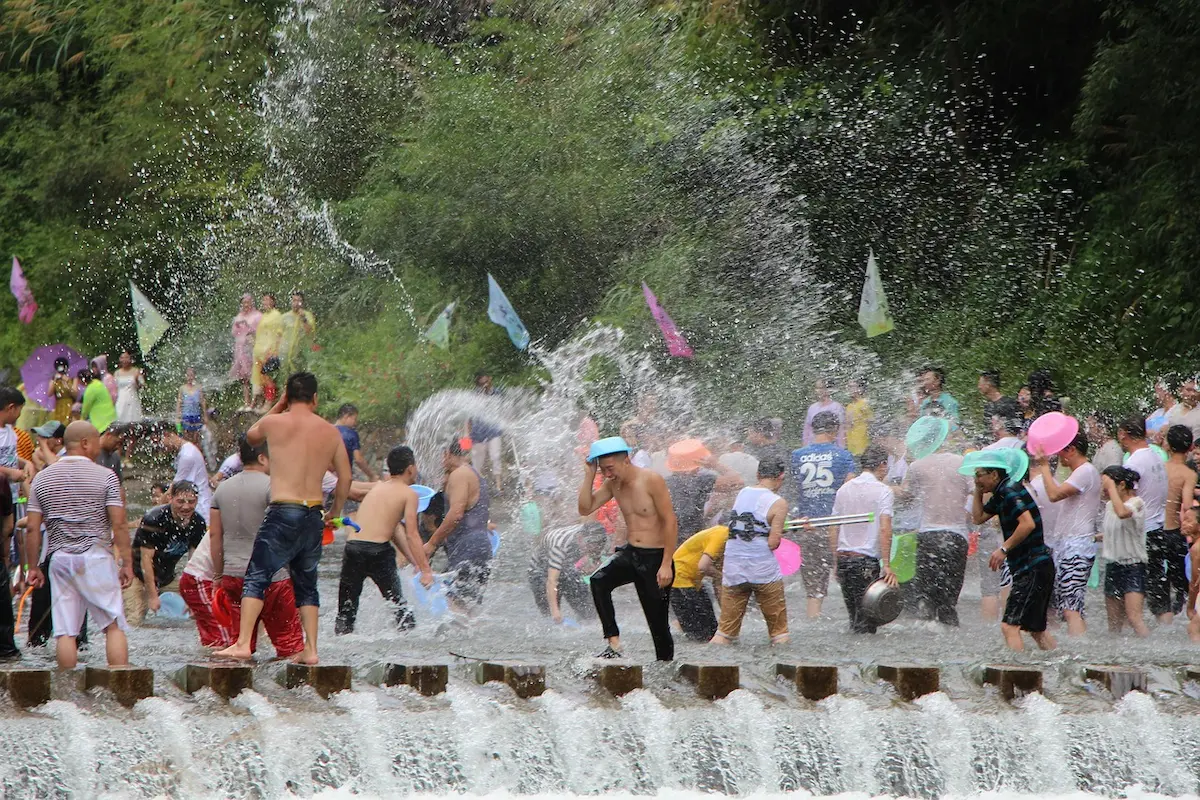 Massive crowd celebrating Songkran with water splashes and colorful buckets