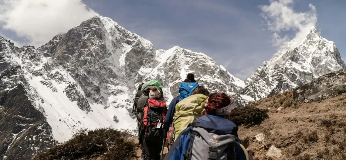 Group of trekkers hiking towards snow-capped Himalayan peaks in Nepal under clear blue skies