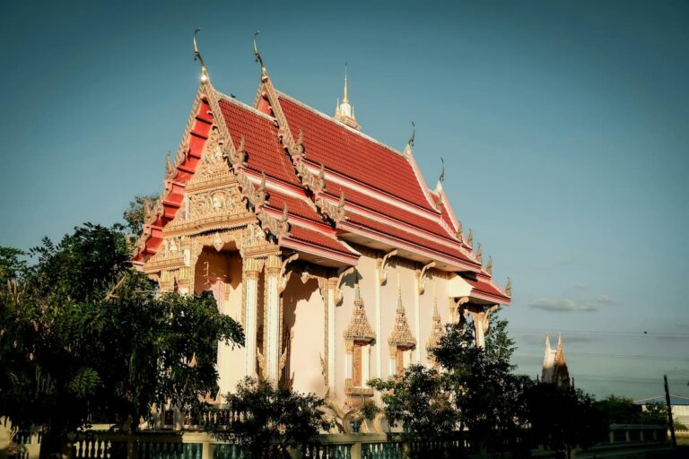 Thai Buddhist temple with ornate red roof and golden details under a clear blue sky in Phuket
