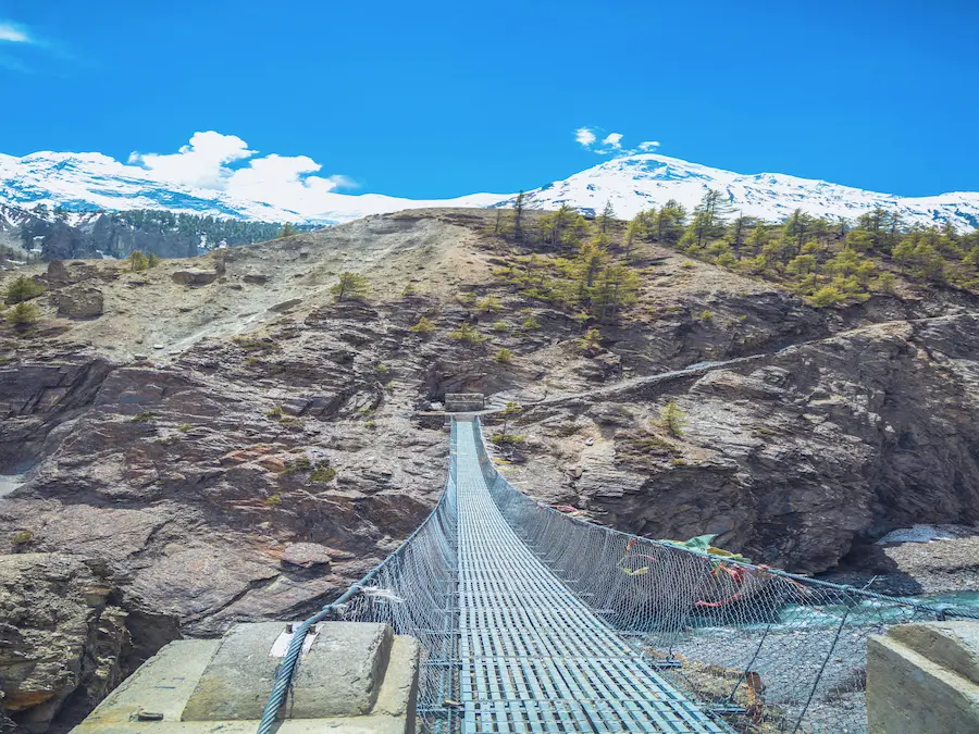 Trekker crossing a Himalayan suspension bridge in Manang, Nepal