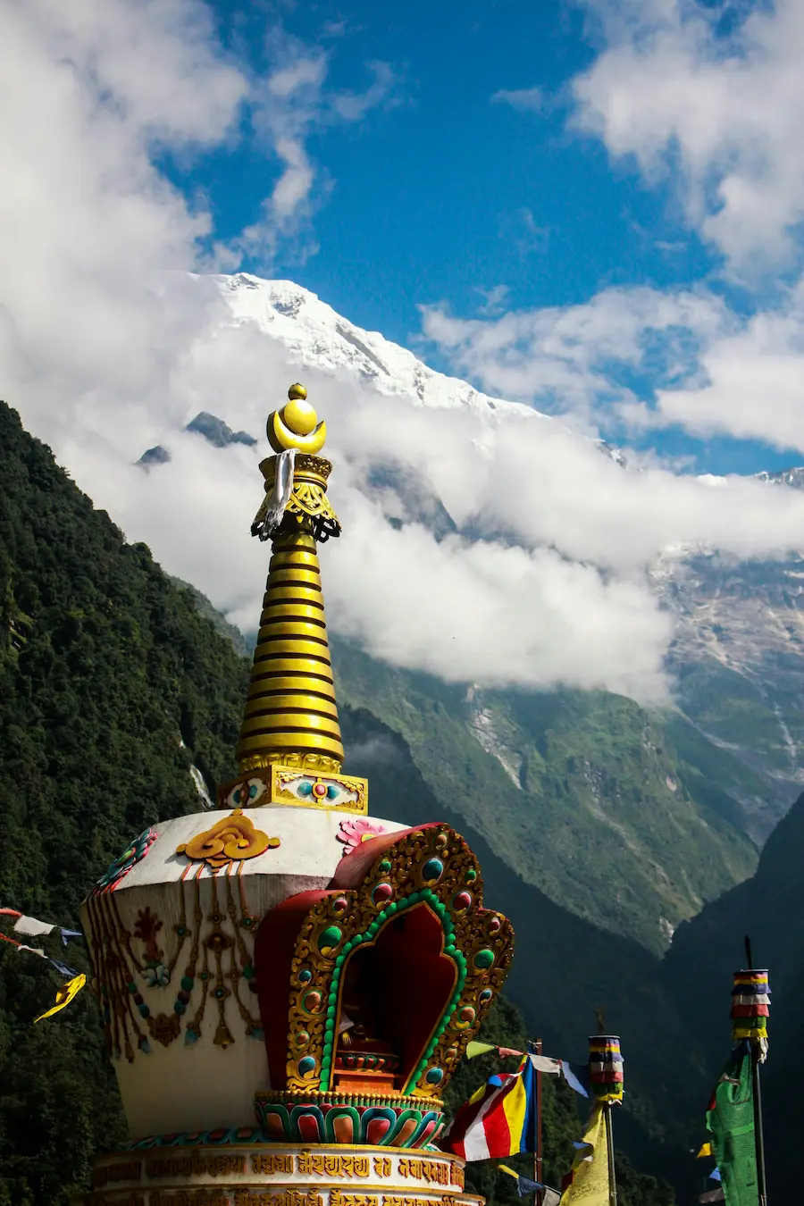 Stone chorten draped in prayer flags with Himalayan peaks in the background