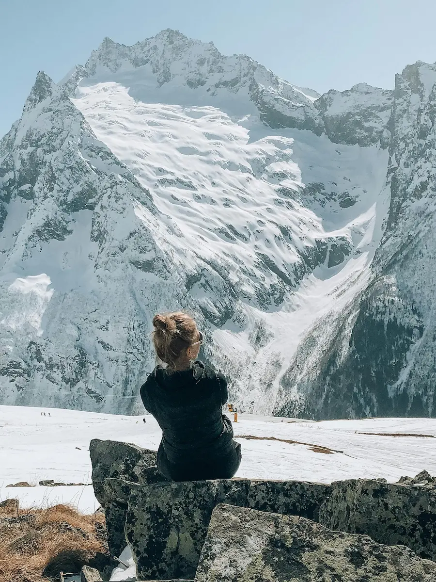 Hiker resting with Machhapuchhre (Fishtail) and the Annapurna range beyond at golden hour
