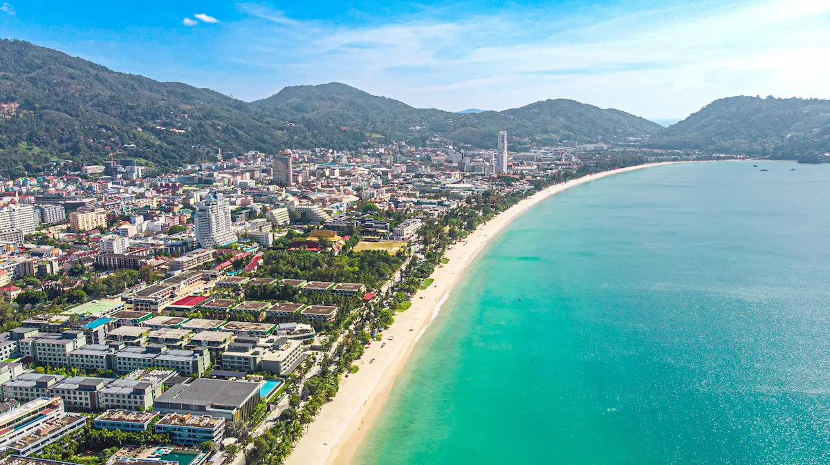 Aerial view of Patong Beach Thailand with turquoise water, long sandy shoreline and the city backed by green hills